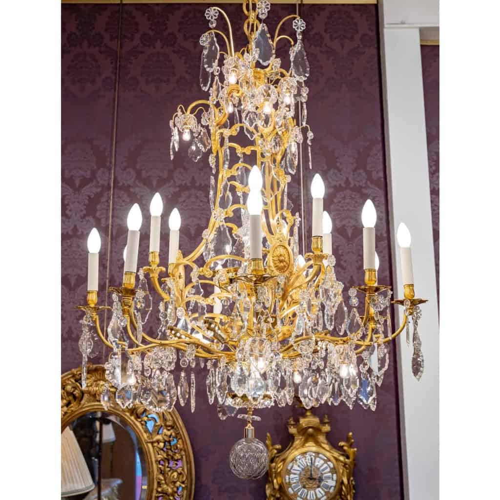 Lustre en bronze doré à 16 bras de lumière et 12 fleurettes en cristal éclairées, XIXème siècle ||||||||||