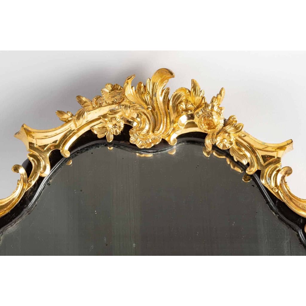 Un miroir mural ou à poser de style Napoléon III en bronze doré et bois noirci. Un miroir mural ou à poser de style Napoléon III en bronze doré et bois noirci.