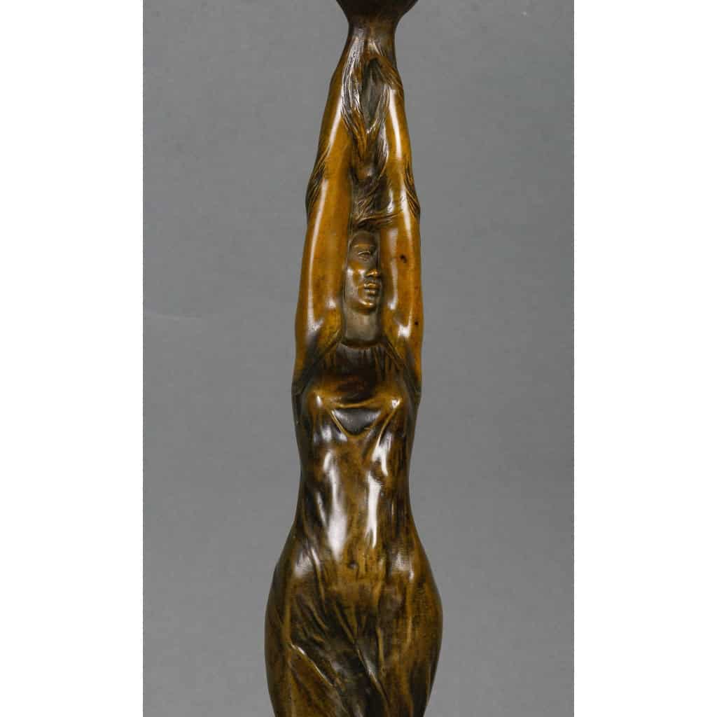 Lampe en bronze patiné représentant une femme retenant une tulipe en pâte de verre. Époque Art Nouveau vers 1900. Signée Firmin Bate Lampe en bronze patiné représentant une femme retenant une tulipe en pâte de verre. Époque Art Nouveau vers 1900. Signée Firmin Bate