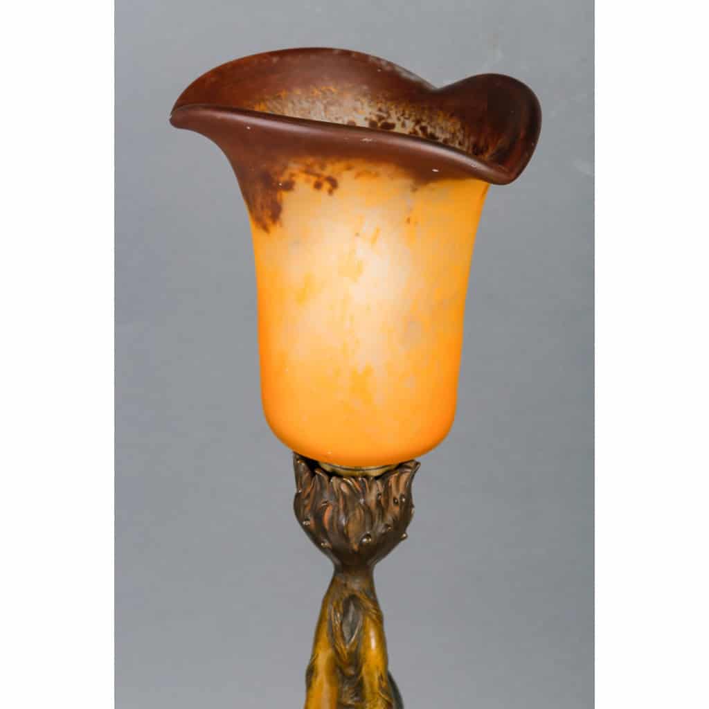 Lampe en bronze patiné représentant une femme retenant une tulipe en pâte de verre. Époque Art Nouveau vers 1900. Signée Firmin Bate Lampe en bronze patiné représentant une femme retenant une tulipe en pâte de verre. Époque Art Nouveau vers 1900. Signée Firmin Bate