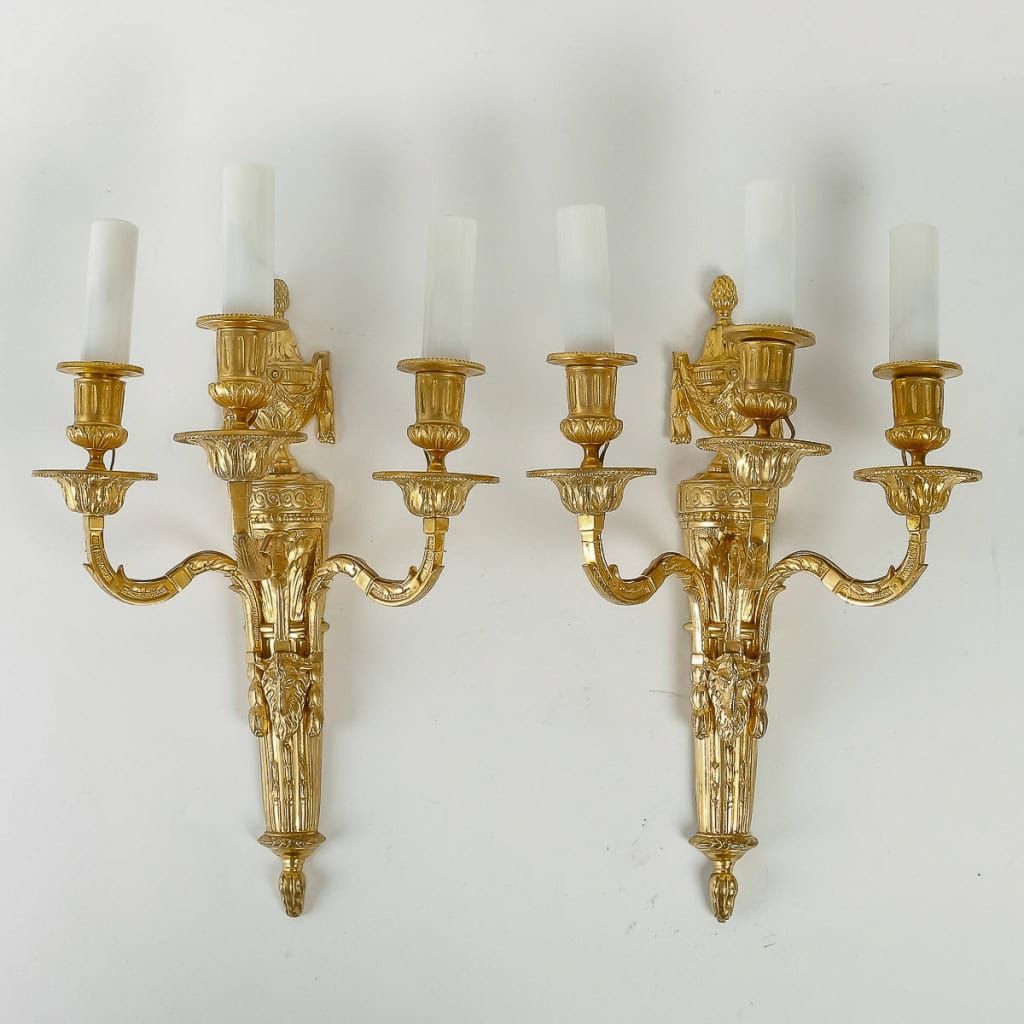 Paire d'appliques à têtes de Bélier à trois bras de lumières en bronze ciselé et doré de style Louis XVI vers 1890 Paire d'appliques à têtes de Bélier à trois bras de lumières en bronze ciselé et doré de style Louis XVI vers 1890