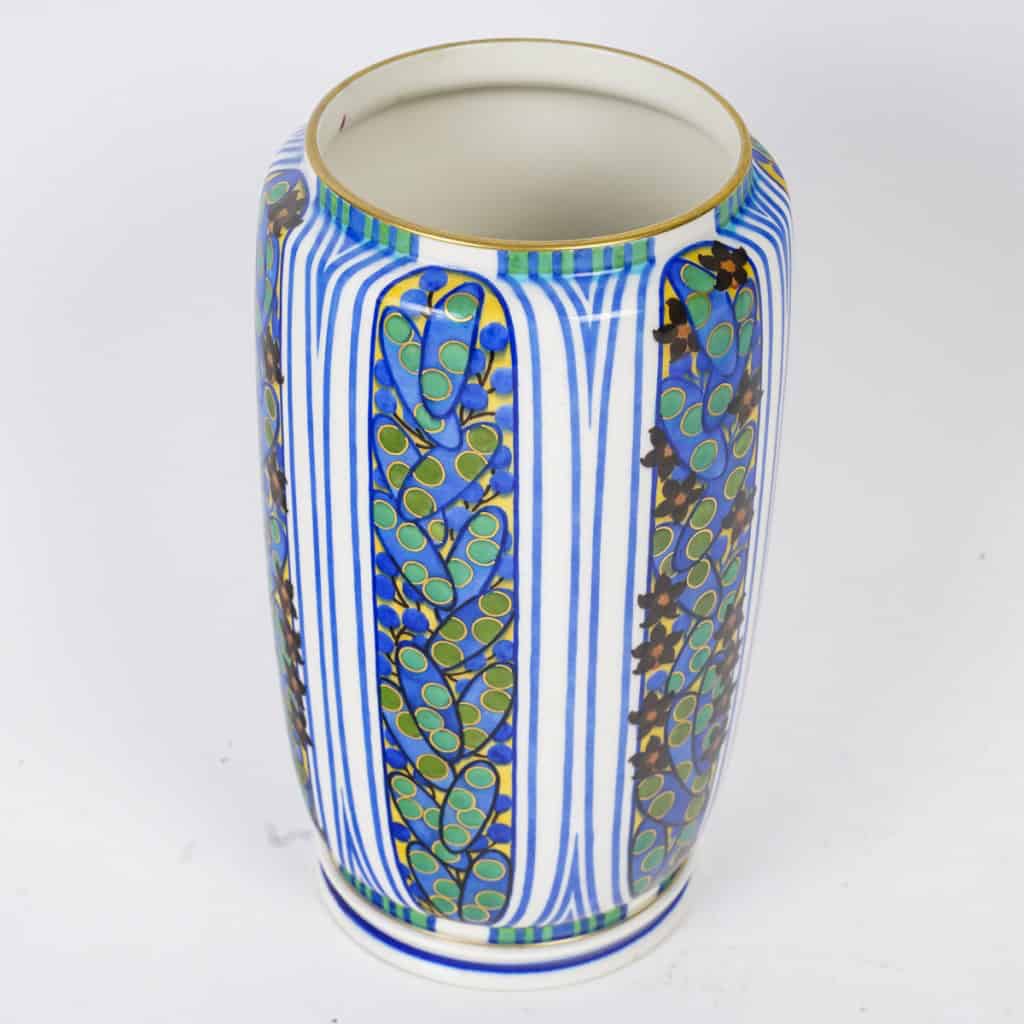 Très élégant vase en porcelaine blanche à décor abstrait végétalisant géométriques dans les tons de bleu, vert, noir, jaune et rouge. Pièce signée, au cachet de la Manufacture National de Sèvres, décor peint d’après l’artiste Jane Levy, travail de 1925. 