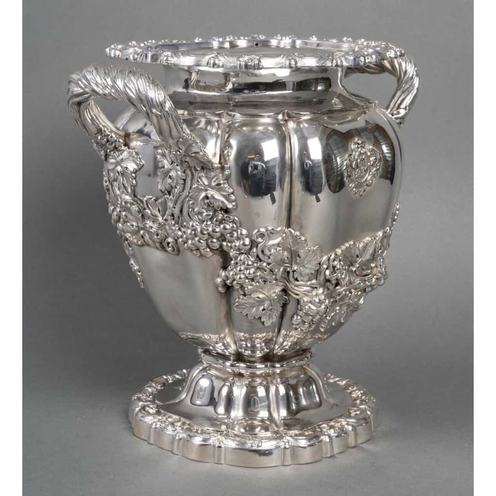 CHARLES NICOLAS ODIOT – Rafraichissoir en argent d’époque Charles X vers 1818/1838 CHARLES NICOLAS ODIOT – Rafraichissoir en argent d’époque Charles X vers 1818/1838 Rafraichissoir en argent massif de forme « Médicis » la base ronde chantournée est décorée d’arabesques et de fleurettes formant piédouche sur lequel est posé le vase ovoïde à côtes de melon, entièrement décoré en applique de feuillages et de grappes de raisins qui se termine par l’émergence de deux anses latérales. Le col est également orné d’une frise d’arabesques. Ecusson monogrammé. Dimensions : hauteur 25 cm – largeur au col 24 cm Diamètre base 16 cm Matière : Argent 1er titre 950/°°° Poids : 2 120 grammes Poinçon : VIEILLARD/PARIS Epoque : 1818/1838 Orfèvre : CHARLES NICOLAS ODIOT Origine : France/Paris