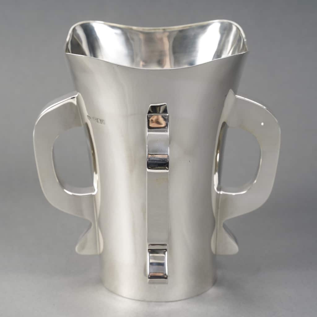 Orfèvre G & S. Ltd - VASE MODERNiSTE EN ARGENT MASSIF LONDRES 1916 Orfèvre G & S. Ltd - VASE MODERNiSTE EN ARGENT MASSIF LONDRES 1916 Exceptionnel Vase moderniste en argent massif base ronde légèrement évasé vers le col, corps uni flanqué de quatre anses de style transition entre l’art nouveau et l’art déco. Pièce très originale exécutée au début du XXe siècle. Très bon état. Dimensions : hauteur 20,5 cm – diamètre base 9,9 cm – diamètre col 17 cm Matière : Argent 1er titre 925/1°°° Poids : 854 grammes Poinçon : ARGENT LONDRES 1916 Epoque : EDOUARD VII Orfèvre : Goldsmiths' & Silversmiths' Company Ltd Origine : LONDRES/GRANDE BRETAGNE Biographie : Cette grande entreprise de bijouterie et d'orfèvrerie de détail a été fondée en 1880 au 112 Regent Street. Les associés d'origine étaient William Gibson et John Lawrence Langman. Après l'absorption en 1893 de la Goldsmiths' Alliance Ltd, la Goldsmiths & Silversmiths Co a été transformée en société à responsabilité limitée. En 1952, la société a fusionné avec Garrard & Co. Bibliographie : John Culme, « Le répertoire des orfèvres et des argentiers 1838-1914 », Woodbridge 1987