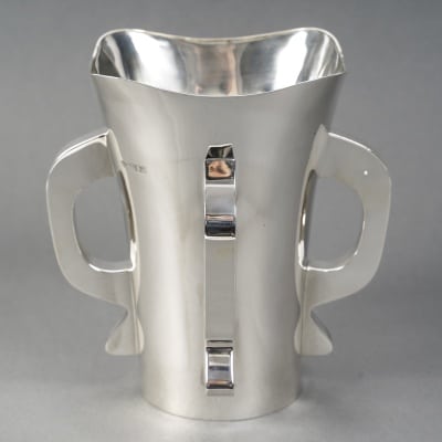 Orfèvre G & S. Ltd - VASE MODERNiSTE EN ARGENT MASSIF LONDRES 1916 Exceptionnel Vase moderniste en argent massif base ronde légèrement évasé vers le col, corps uni flanqué de quatre anses de style transition entre l’art nouveau et l’art déco. Pièce très originale exécutée au début du XXe siècle. Très bon état. Dimensions : hauteur 20,5 cm – diamètre base 9,9 cm – diamètre col 17 cm Matière : Argent 1er titre 925/1°°° Poids : 854 grammes Poinçon : ARGENT LONDRES 1916 Epoque : EDOUARD VII Orfèvre : Goldsmiths' & Silversmiths' Company Ltd Origine : LONDRES/GRANDE BRETAGNE Biographie : Cette grande entreprise de bijouterie et d'orfèvrerie de détail a été fondée en 1880 au 112 Regent Street. Les associés d'origine étaient William Gibson et John Lawrence Langman. Après l'absorption en 1893 de la Goldsmiths' Alliance Ltd, la Goldsmiths & Silversmiths Co a été transformée en société à responsabilité limitée. En 1952, la société a fusionné avec Garrard & Co. Bibliographie : John Culme, « Le répertoire des orfèvres et des argentiers 1838-1914 », Woodbridge 1987