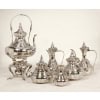 Orfèvre Duponchel - Service thé café en argent massif style Ottoman XIXe Orfèvre Duponchel - Service thé café en argent massif style Ottoman XIXe Service thé / café en argent massif dans le goût ottoman comprenant une cafetière, une théière, un crémier et un sucrier couvert , une verseuse à eau chaude en argent et son samovar et son brûleur sur un trépiéd en métal argenté. Chaque pièce est entièrement gravée à l'acide de motifs orientaux sur fond amati, le corps est ceinturé de quatre filets. L'intérieur du sucrier et du pot à lait est légèrement vermeillé. Dimensions SAMOVAR : hauteur 45 cm - Cafetière: hauteur 26 cm Matières : Argent massif ( 5 pièces) et métal argenté pour le samovar. Poinçon : Minerve 1er titre Epoque : vers 1865 Ces cinq pièces portent le monogramme "L L" provenance FAMILLE LAZARD.