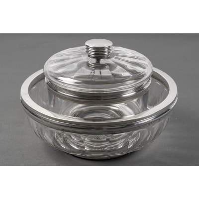 BACCARAT - BOL A CAVIAR EN CRISTAL TAILLE DEUX PIECES XXè ART DECO BOL A CAVIAR en cristal de BACCARAT, taillé de larges languettes et monté sur une batte ronde cerclée d’argent massif sur fond étoilé. Sur ce fond vient s’encastrer un pot en cristal uni cerclé d’argent au col, avec un couvercle taillé de languettes plates, surmonté d’une prise cylindrique en argent .Dimensions : BOL : Diamètre au col 25,5 cm – Diamètre base 14,5 cm – hauteur 10 cm POT : diamètre au col 17 cm – Diamètre base 10,5 cm - hauteur 15 cm Matières : CRISTAL & ARGENT Poinçon : MINERVE Poids brut : 3 845 Grammes Epoque : ART DECORATIF vers 1930 Provenance : CRISTALLERIES DE BACCARAT Origine : France/Paris