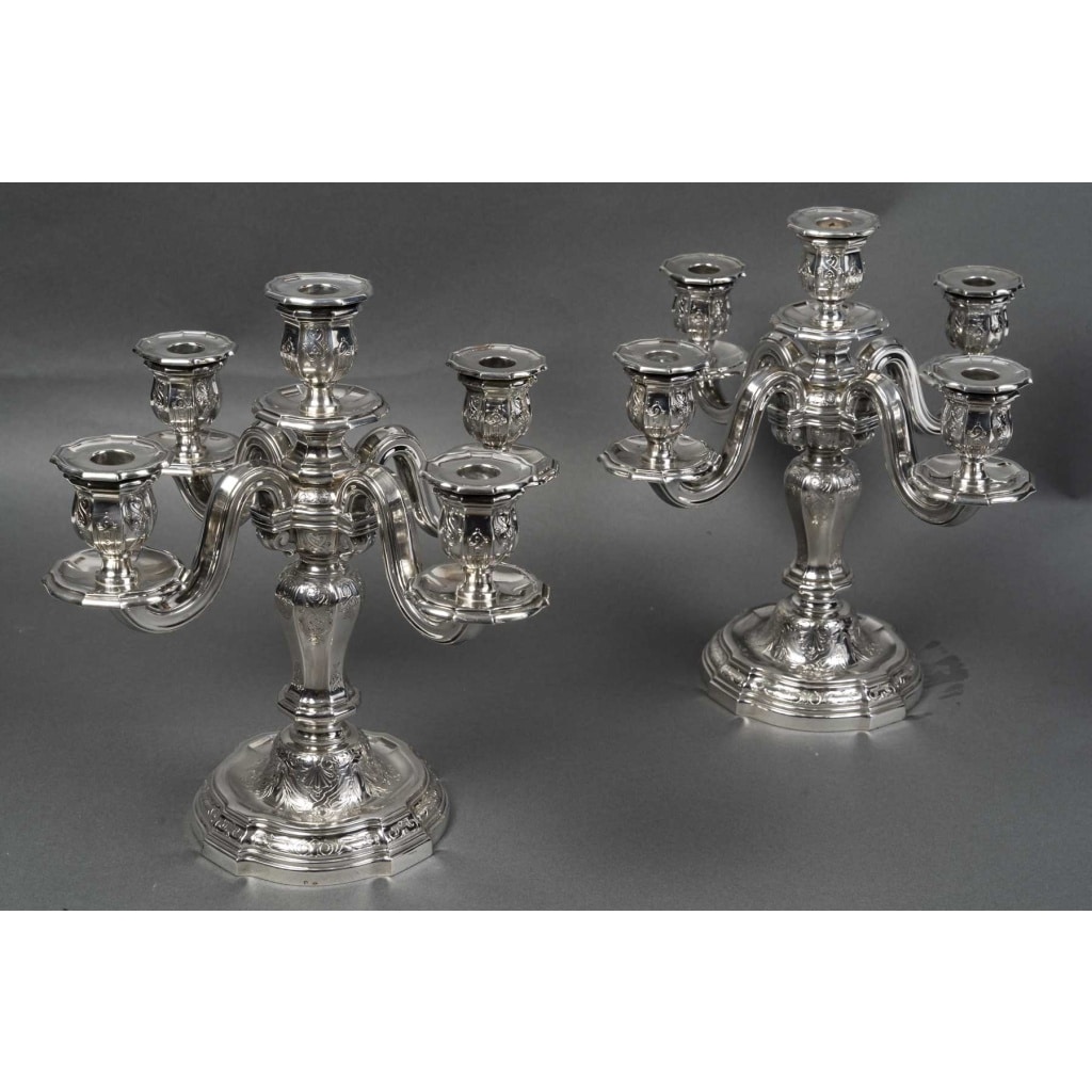 Orfèvre TETARD – Paire de Candélabres 5 lumières en argent massif XXe Orfèvre TETARD – Paire de Candélabres 5 lumières en argent massif XXe Paire de candélabres en argent massif, base ronde à doucine surmontée d’un fût à pans octogonaux supportant un bouquet à quatre bras de lumière plus une centrale. La base, le fût et les binets sont gravés et ciselés d’un décor à la Bérain dans le style «Régence ». Dimensions : Hauteur 33 cm – entraxe 35 cm Matière : Argent 1er titre 950/1°°° Poids : 4 240 grammes Poinçon : MINERVE Epoque : XXè vers 1925 Orfèvre : TETARD à PARIS Origine : France/Paris