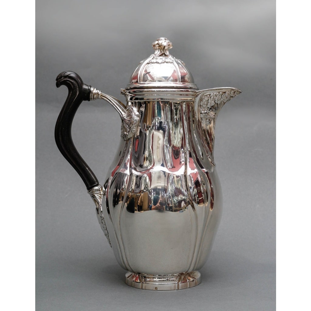 LELIÈVRE (Eugène-Alfred) – Cafetière en argent Massif TIFFANY circa 1880 ART NOUVEAU LELIÈVRE (Eugène-Alfred) – Cafetière en argent Massif TIFFANY circa 1880 ART NOUVEAU Grande Cafetière en argent massif à fond plat, corps ovoïde, anse en ébène sculpté, fixé avec un décor de fleurs en ombelle. On retrouve ce même décor sous le bec verseur et sur la prise du couvercle à charnière. Dimensions : Hauteur : 26 cm – largeur 19 cm diamètre base 13 cm Matière : Argent 1er titre 950/°°° Poids : 1000 grammes Poinçon : MINERVE Epoque : ART NOUVEAU vers 1880 Orfèvre : E. LELIEVRE Provenance : Edward CHANDLER MOORE (1827/1891) Orfèvre directeur de l’atelier de TIFFANY. – Appartenance Collection H. descendance du Précédent. Nombreuses pièces de sa collection sont exposées au M.M.A. de NEW-YORK. LELIÈVRE (Eugène-Alfred), élève de MM. Mittenholf et Philippe May- Boulevard. Richard-Lenoir, Paris né en 1856, à Montmartre, à la fin de sa vie en 1945 il demeurait 16 rue du grand prieuré Paris 16 -ème. Son atelier était au 14 bis rue des Minimes, Paris. Lelievre a exposé à La Société des Artistes Décorateurs, La Société des Artistes Français et La Société Nationale des Beaux-Arts EXPOSITION DES ARTISTES DECORATEURS dans la revue Le Panthéon de l’industrie de 1906.