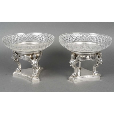 GUSTAVE ODIOT – Paire de coupes argent et cristal Baccarat XIXé Paire de coupes en argent massif dont la base triangulaire est bordée d’une frise de feuilles d’eau surmontée de trois magnifiques sphinges ailées à pattes de Lion, lesquels supportent une coupe ronde en cristal de Baccarat posée sur leur réceptacle en argent. Dimensions : Hauteur 19 cm – Diamètre coupe en cristal 24 cm – Diamètre du réceptacle : 17 cm Matières : Argent 1er titre 950/°°° & Cristal Poids net : 1.395 grammes Poids brut : 3035 grammes Poinçon : MINERVE Epoque : Fin XIXe vers 1880 Orfèvre : GUSTAVE ODIOT Origine : France/Paris Bibliographie : Livre « ODIOT l’Orfèvre » par Olivier Gaub du Gers. Page 99.